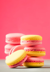 Fototapeta na wymiar Pink yellow macaroons on soft pink background table, place for text, minimalism style