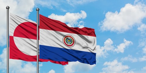 Greenland and Paraguay flag waving in the wind against white cloudy blue sky together. Diplomacy concept, international relations.