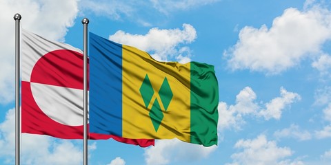 Greenland and Saint Vincent And The Grenadines flag waving in the wind against white cloudy blue...