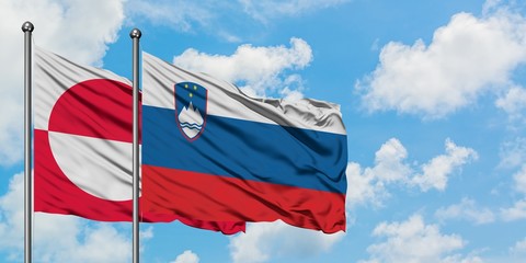 Greenland and Slovenia flag waving in the wind against white cloudy blue sky together. Diplomacy concept, international relations.