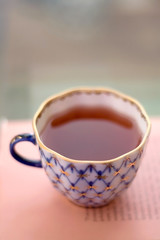 Cup of tea on pink book. Selective focus.