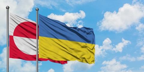 Greenland and Ukraine flag waving in the wind against white cloudy blue sky together. Diplomacy concept, international relations.