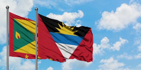 Grenada and Antigua and Barbuda flag waving in the wind against white cloudy blue sky together....