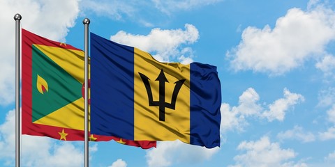 Grenada and Barbados flag waving in the wind against white cloudy blue sky together. Diplomacy concept, international relations.
