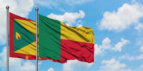 Grenada and Benin flag waving in the wind against white cloudy blue sky together. Diplomacy concept, international relations.