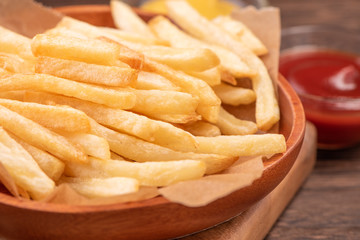Golden yummy deep French fries on kraft baking sheet paper and serving tray to eat with ketchup and yellow mustard, close up, lifestyle.