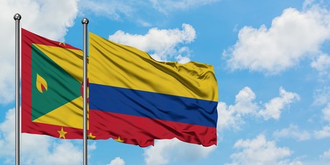 Grenada and Colombia flag waving in the wind against white cloudy blue sky together. Diplomacy...
