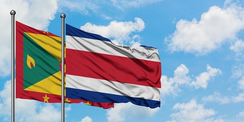 Grenada and Costa Rica flag waving in the wind against white cloudy blue sky together. Diplomacy concept, international relations.