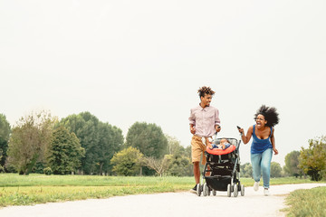 Happy African family having fun together in public park - Black mother father and baby daughter...