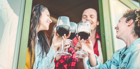 Happy friends having fun toasting with red wine outdoor - Group of young people cheering and...