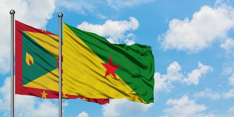Grenada and French Guiana flag waving in the wind against white cloudy blue sky together. Diplomacy concept, international relations.