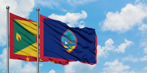 Grenada and Guam flag waving in the wind against white cloudy blue sky together. Diplomacy concept, international relations.