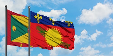 Grenada and Guadeloupe flag waving in the wind against white cloudy blue sky together. Diplomacy concept, international relations.