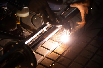 The worker is welding metal part of the details of the system rolling lifting gate. Selective focus..
