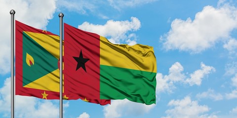 Grenada and Guinea Bissau flag waving in the wind against white cloudy blue sky together. Diplomacy...