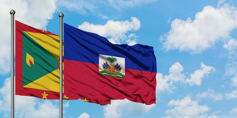 Grenada and Haiti flag waving in the wind against white cloudy blue sky together. Diplomacy...