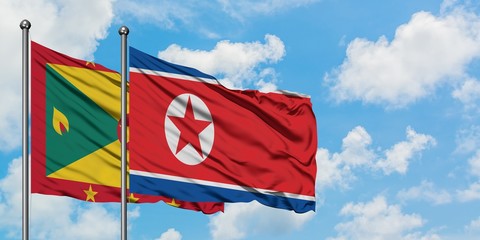 Grenada and North Korea flag waving in the wind against white cloudy blue sky together. Diplomacy concept, international relations.