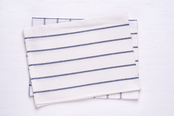 Kitchen towels with blue stripes on white wooden table top. Mock up for design. Top view