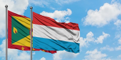 Grenada and Luxembourg flag waving in the wind against white cloudy blue sky together. Diplomacy concept, international relations.