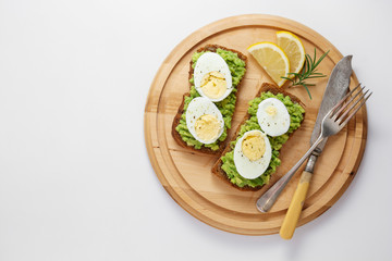 Avocado toast. Sandwich with egg, mashed on wholegrained bread on cutting board. Healthy breakfast.