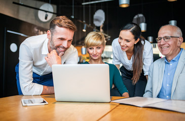 Obraz premium Group of business people with laptop meeting in cafe