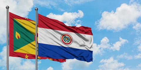 Grenada and Paraguay flag waving in the wind against white cloudy blue sky together. Diplomacy...