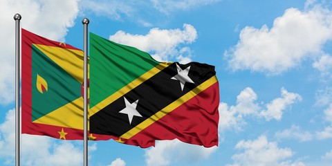 Grenada and Saint Kitts And Nevis flag waving in the wind against white cloudy blue sky together....