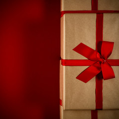 Brown christmas gifts with red ribbon and bow on dark mood red background. Free space for your product or text. Copy space, flat lay, Aerial view. Cold winter december time.Xmas time.