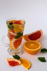 refreshing cocktail with slices of fresh orange and grapefruit with green mint leaves on white background. Detox citrus cocktail. healthy lifestyle. Fresh citrus fruit on white background.