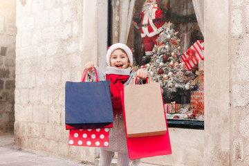 Christmas shopping, gift buying for family and friends. Child girl presents paper bags on market...