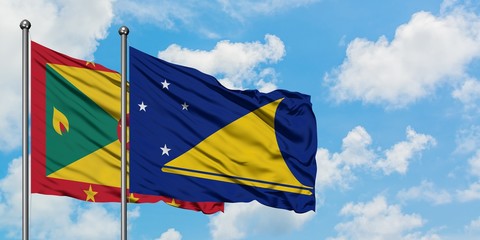 Grenada and Tokelau flag waving in the wind against white cloudy blue sky together. Diplomacy concept, international relations.
