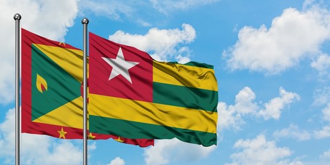 Grenada and Togo flag waving in the wind against white cloudy blue sky together. Diplomacy concept, international relations.