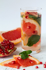 Detox citrus cocktail. healthy lifestyle. Refreshing summer homemade cocktail with ripe grapefruit and red pomegranate fruit on white background.