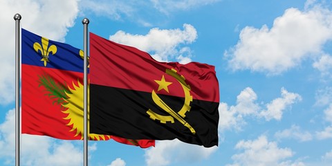 Guadeloupe and Angola flag waving in the wind against white cloudy blue sky together. Diplomacy concept, international relations.