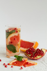 Detox citrus cocktail. healthy lifestyle. Refreshing summer homemade cocktail with ripe grapefruit and pomegranate fruit on white background.