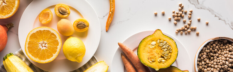 panoramic shot of plates with vegetables and fruits near chickpea on marble surface