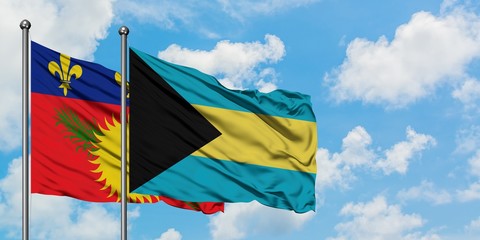 Guadeloupe and Bahamas flag waving in the wind against white cloudy blue sky together. Diplomacy concept, international relations.