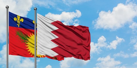 Guadeloupe and Bahrain flag waving in the wind against white cloudy blue sky together. Diplomacy concept, international relations.