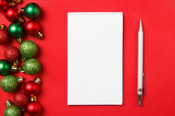 Christmas gifts shopping planning. Notebook with christmas balls on red background. New year goals.