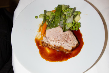 Green pea pods and pork steak on sauce white plate plate