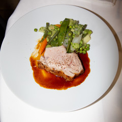 Sliced homemade roasted meat loaf with  peas in a white plate