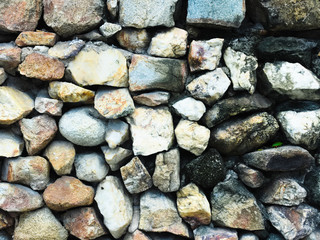 Background, a stone wall made of many granite stones. Weathered gray stone wall