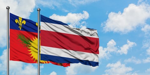 Guadeloupe and Costa Rica flag waving in the wind against white cloudy blue sky together. Diplomacy concept, international relations.