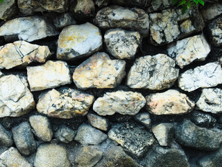 Background, a stone wall made of many granite stones. Weathered gray stone wall