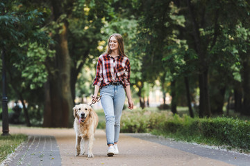 full length view of beautiful girl in casual clothes waking in park with golden retriever © LIGHTFIELD STUDIOS