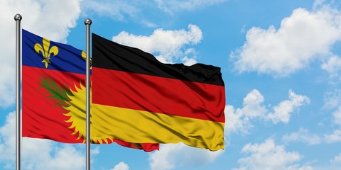 Guadeloupe and Germany flag waving in the wind against white cloudy blue sky together. Diplomacy concept, international relations.