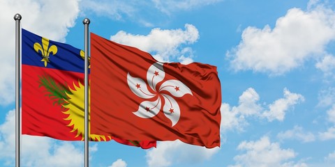 Guadeloupe and Hong Kong flag waving in the wind against white cloudy blue sky together. Diplomacy concept, international relations.