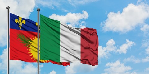 Guadeloupe and Italy flag waving in the wind against white cloudy blue sky together. Diplomacy concept, international relations.