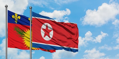 Guadeloupe and North Korea flag waving in the wind against white cloudy blue sky together. Diplomacy concept, international relations.