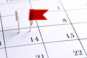 Red pin on a date on a calendar closeup. Important date. Place for text. Planning concept.